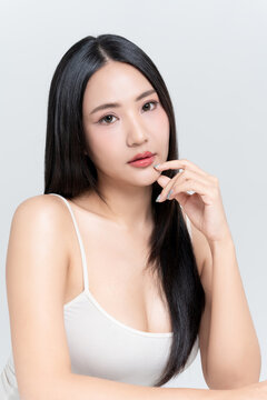 Happy young Asian woman finger touching on mouth with glowing face natural makeup and healthy black hair isolated on white background, for advertising about lipstick, skincare and cosmetics concept.