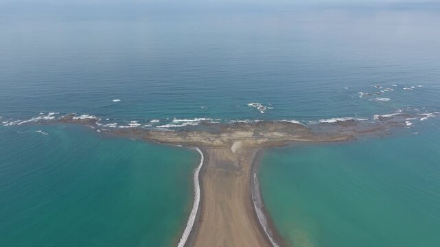 Aerial view of the Whale Tail sandbar at Marino Ballena National Park surrounded by turquoise ocean waters and gentle waves along the coastline of Costa Rica.