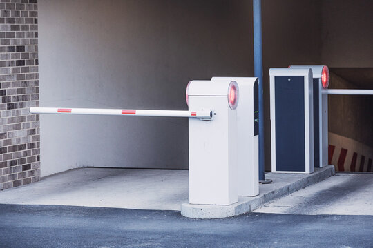 Parking barrier arm is down, controlling vehicle access to a modern underground garage entrance, ensuring security and traffic management