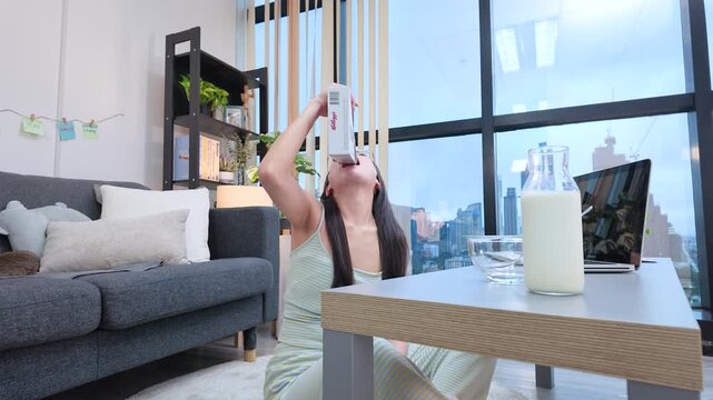 Asian Woman Pouring Breakfast Cereal Directly into Her Mouth at Home