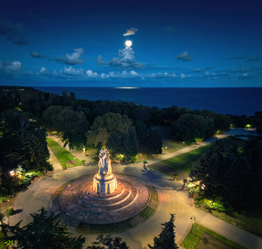 Aerial view of illuminated monument and Sea Garden park at night with full moon over Black Sea, Varna , Bulgaria