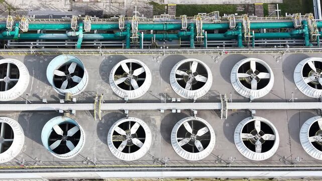 Aerial view of industrial ventilation system with multiple large fans and ducts operating in a plant, showcasing the continuous airflow and mechanical design across the facility