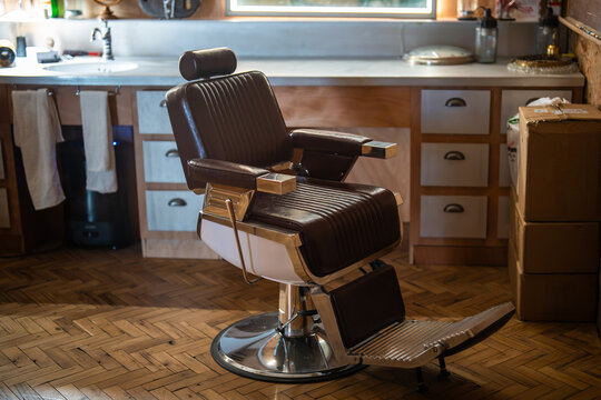 Cozy interior of barbershop with classic vintage chairs, illuminated mirrors and professional grooming tools arranged on counters for clients, indoor setting of hair salon with stylish furniture.