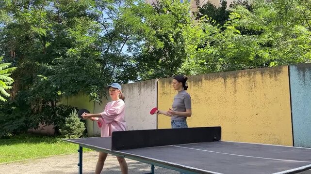 Outdoor sport - two Women Engage In Lively Table Tennis Game