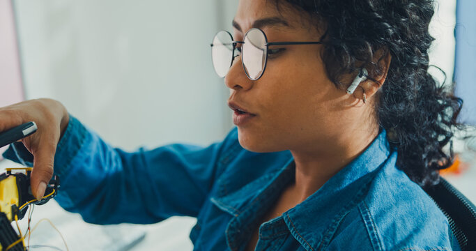 Close-up African American female robotics engineer discussing mechanical part on video call in laboratory. Remote work, virtual training, online meeting, future technology, technical support concept.