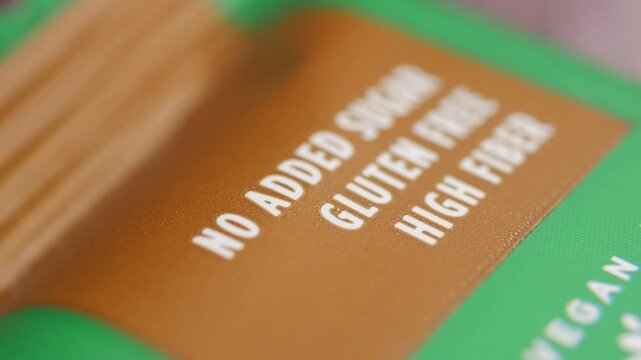 A close-up view of a product label highlighting its healthy features with &ldquo;no added sugar, gluten free, high fiber&rdquo; text in a slow-motion cinematic shot.
