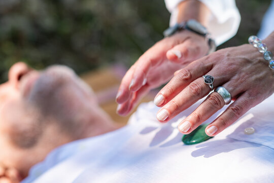 Practitioner positioning hands above the chest with a healing crystal placed over the heart area during a spiritual energy and guided meditation practice.