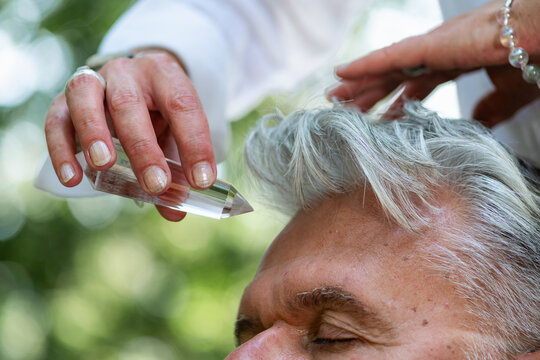 Crystal healing practitioner holding a clear crystal near a man&rsquo;s head during a spiritual healing session focused on energy work, mindfulness, guided meditation, and holistic wellbeing.