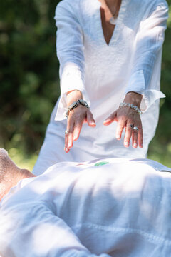 Practitioner holding both hands above a resting man during a crystal healing session, representing energy balancing, guided meditation, mindfulness, and spiritual wellness.