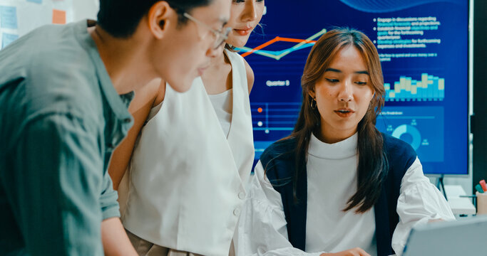Group of Asian businesspeople work together discuss plan idea with investment data profit sale statistics in business meeting in office. Financial generation z team brainstorm on e-Commerce project.