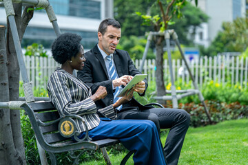 Fototapeta premium Business Professionals Discussing Plans on a Tablet Outdoors