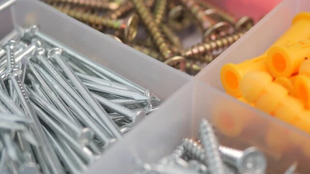 Macro shot of hardware box with screws nails and plastic anchors in slow motion camera movement.