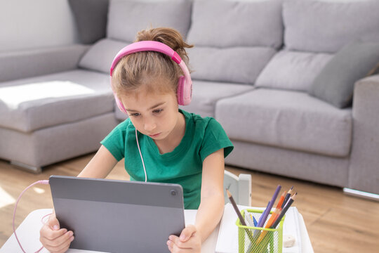 Young girl wearing headphones using tablet for online learning.