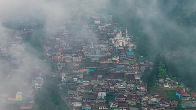 Aerial view of Nepal Van Java village with colorful houses on the slopes of Mount Sumbing surrounded by mist in Magelang, Central Java, Indonesia.