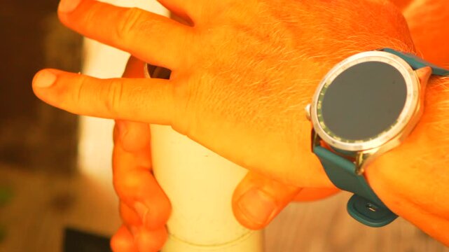 Coffee grinding process using manual grinder by person wearing smartwatch indoors. Close-up tracking shot.