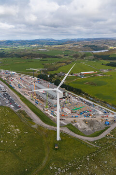 Aerial view of the Green Mountain SVG-Undheim data center construction site with a wind turbine, cranes, and industrial structures set amidst rolling green hills in Undheim, Rogaland, Norway.