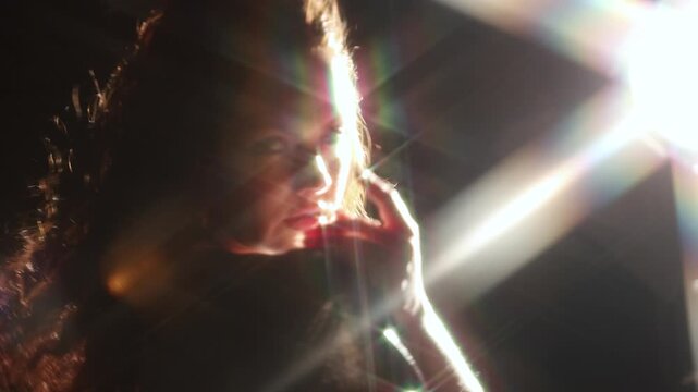 Bright light beam covering the face of a woman in a shiny dress. Anonymous figure, star flare and dark space for themes of energy, insight and change.
