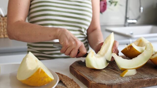 Woman Cutting Melon Into Pieces In The Kitchen Close-Up