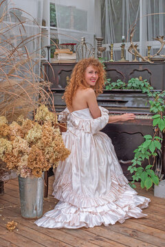 Romantic Victorian Woman in Pink Vintage Dress Sitting in Antique interior