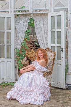 Romantic Victorian Woman in Pink Vintage Dress Sitting in Antique interior