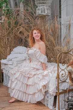 Romantic Victorian Woman in Pink Vintage Dress Sitting in Antique interior