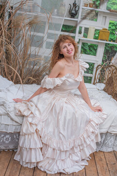 Romantic Victorian Woman in Pink Vintage Dress Sitting in Antique interior