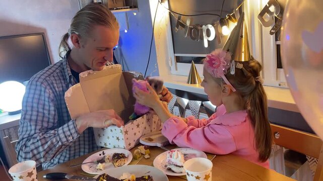 Father and daughter home celebrating birthday together with cake and fairy lights