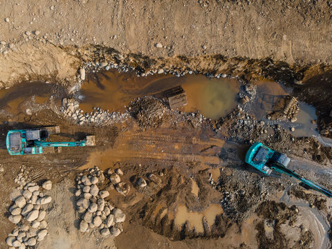 Mining Work of Excavators Operating on Muddy Terrain in a Large-Scale Rock and Sand Quarry in Dawuhan Kulon, Central Java, Indonesia. Heavy Machinery Works Across Wet Ground Viewed from Above.