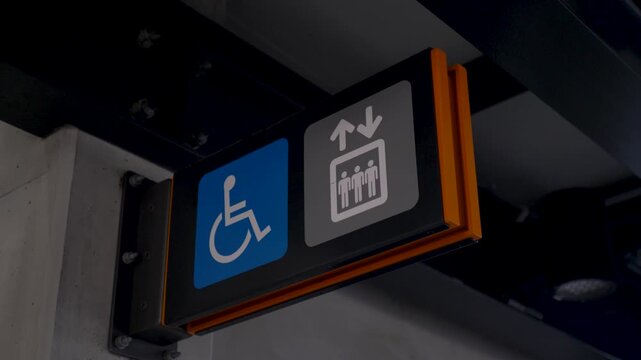 Slow motion close-up of a wheelchair accessible elevator sign symbol for a lift with up and down arrows attached to an urban train station building infrastructure in an Australian suburban rural town