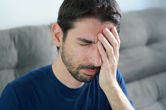 Man covering one side of head and eye in severe migraine attack