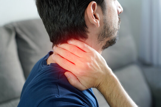 Stiff neck concept. Unidentified young man with stiff neck and red highlight showing muscle tightness.