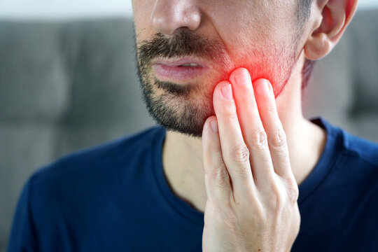 Man holding his cheek while suffering from painful jaw bruxism due to night stress
