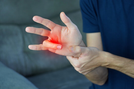 Unrecognizable man trying to force open locked finger suffering from trigger finger with red highlight