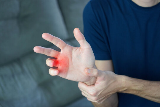 Trigger fingers concept. Unidentified man trying to force open locked fingers suffering from trigger fingers with red highlight.