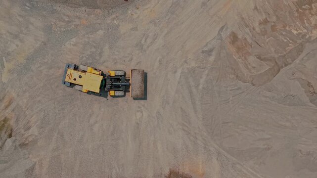Aerial view of a yellow bulldozer working on sandy ground in a quarry in Yogyakarta, Special Region of Yog, Indonesia.