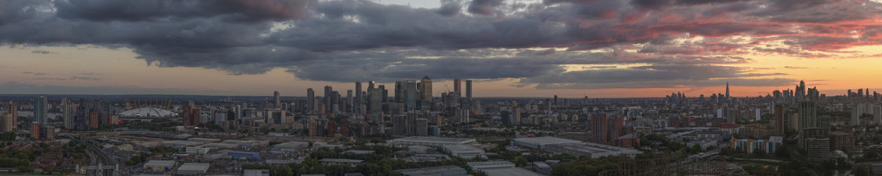 Aerial view of the London skyline at sunrise featuring Canary Wharf and The Shard under a dramatic cloudy sky in London, Greater London, United Kingdom.