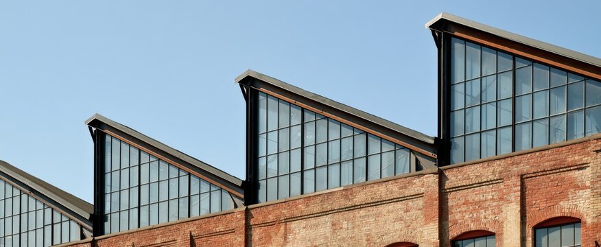 Industrial brick factory sawtooth roofline with steel framed skylight windows for architectural design, poster, background and banner