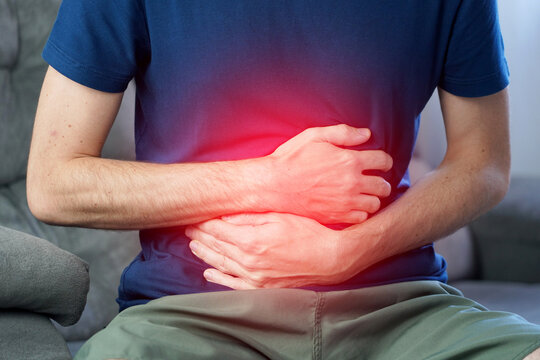 Unrecognizable man pressing hands against flat lower abdomen in severe irritable bowel syndrome IBS pain with red highlight