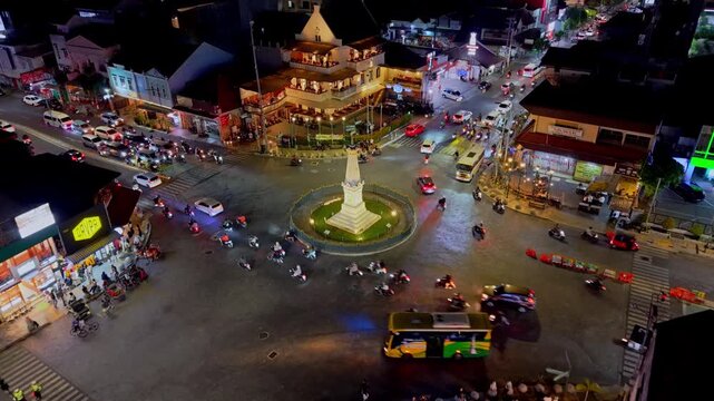 Aerial view of Tugu Yogyakarta Monument illuminated at night with busy traffic and motorcycles circulating the roundabout in Yogyakarta, Special Region of Yogyakarta, Indonesia.