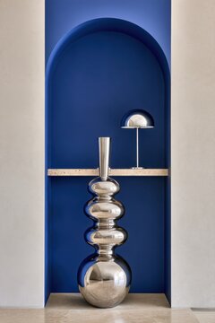 Modern interior decor blue arch niche with metallic vase and chrome lamp for design poster and background and showroom styling for interior inspiration