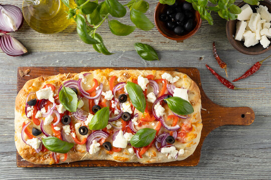 Traditional Roman pinsa with feta cheese, peppers and black olives.