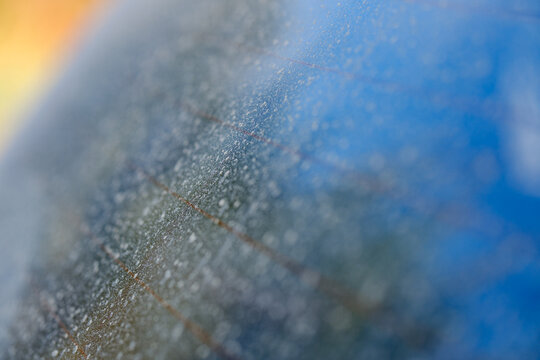 Heavy layer of dry dust and water stains on a vehicle rear windshield glass with heated defroster lines needing a wash