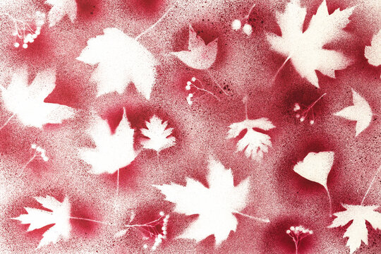Handmade red spray paint art print with white maple leaf silhouettes on textured paper, with a grainy frosted appearance. Lives in festive holiday and retro greeting card design.