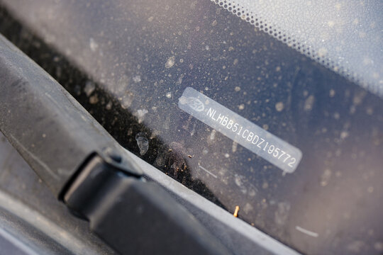 Hyundai vehicle identification number VIN code sticker visible through dirty rear window glass with wiper blade arm