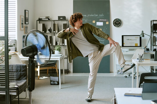 Young adult Caucasian man dancing alone in modern office during work break, expressing joy and freedom. Concept represents positive workplace culture and employee mental wellbeing
