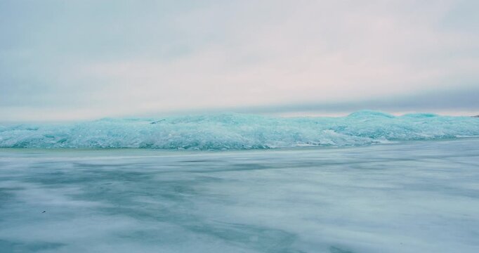 Frozen lake with broken ice formations under a cloudy winter sky