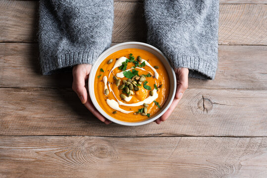 Bowl of pumpkin soup in woman hands