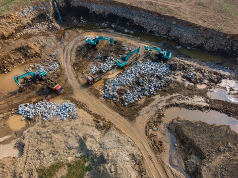 Aerial View of Heavy Earthmoving Machinery Group of Excavators Working in a Large-Scale Rock Ore Quarry. Mining Site Work from Above.
