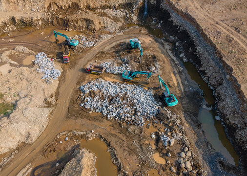 Aerial View of Heavy Earthmoving Machinery Group of Excavators Working in a Large-Scale Rock Ore Quarry. Mining Site Work from Above.