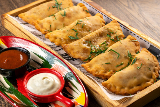 Golden crispy fried chebureki pastries sprinkled with fresh herbs